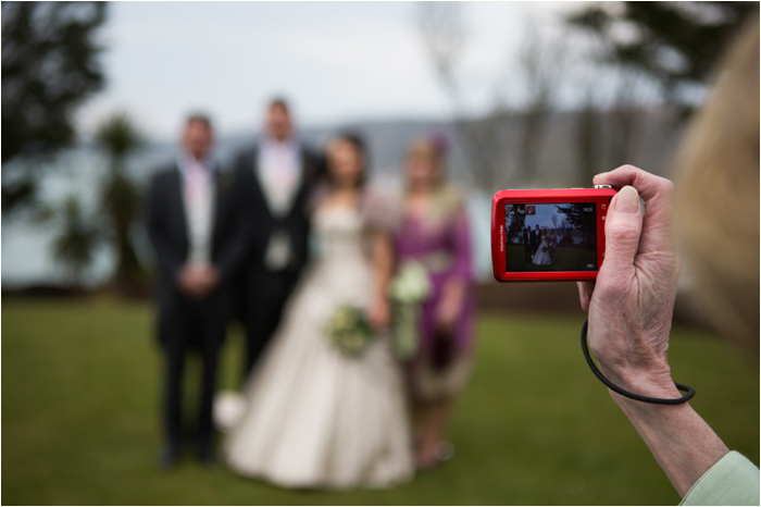 A family member takes wedding pictures outside in Cornwall Wedding Photographer in Cornwall